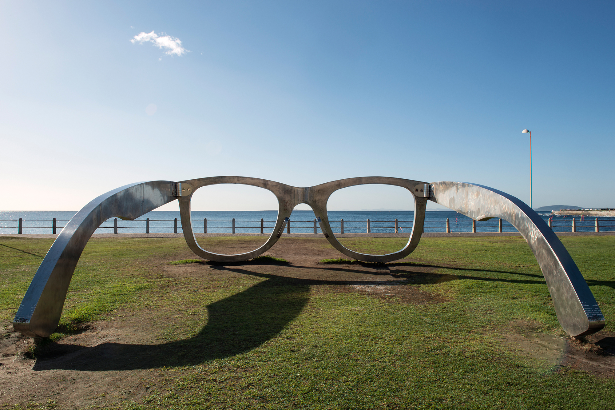 A large sculpture of a pair of metal glasses facing the ocean