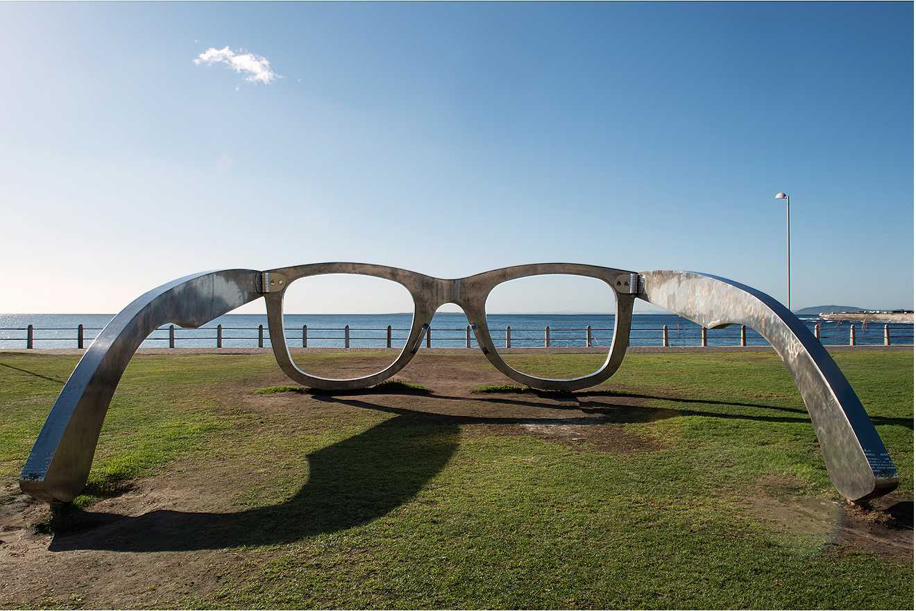 A large sculpture of a pair of metal glasses facing the ocean